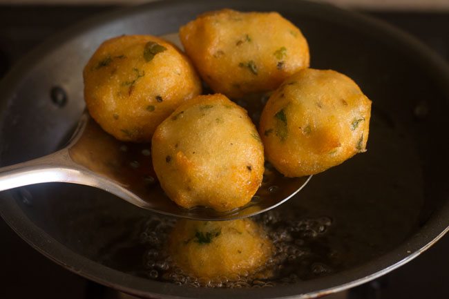 removing fried mix dal vadas with a slotted spoon. 