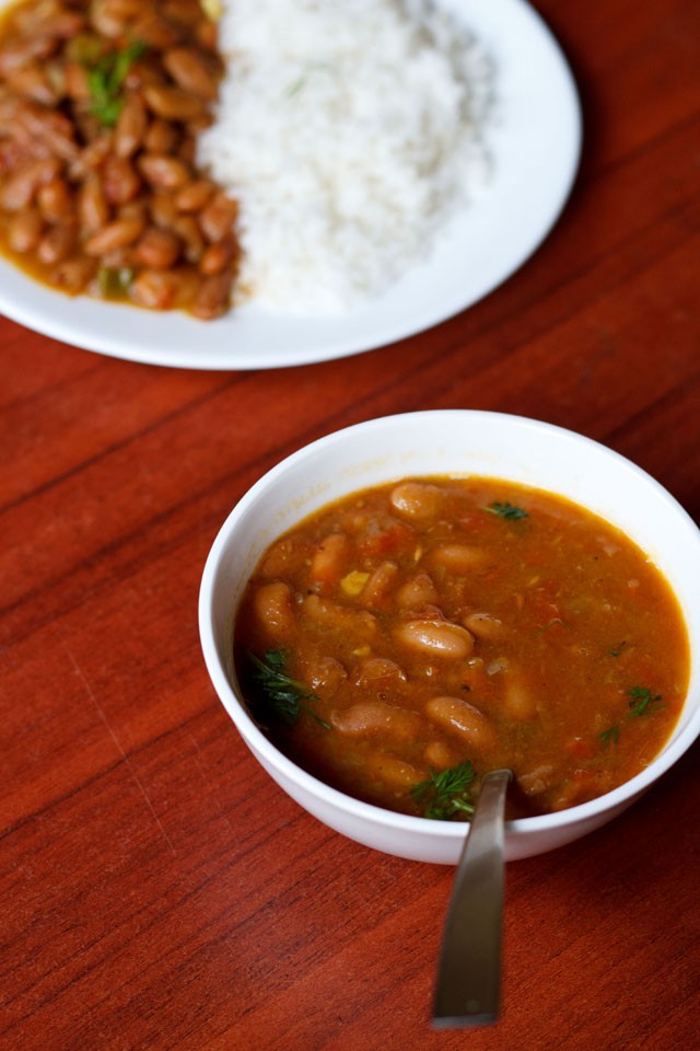 rajma chawal served on a white plate with a side of rajma in a white bowl with spoon. 