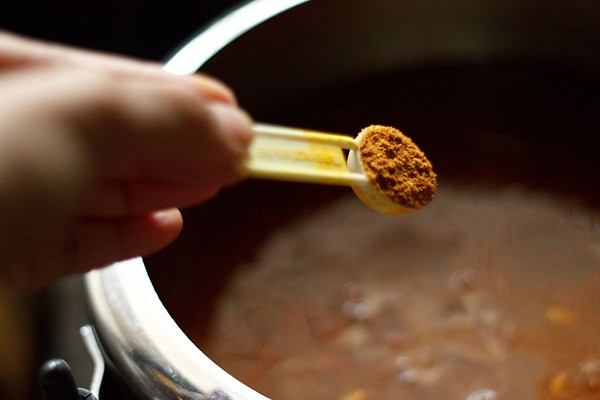 adding garam masala powder to rajma curry in cooker. 