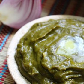 Palak saag in a earthen bowl with melted butter on top.