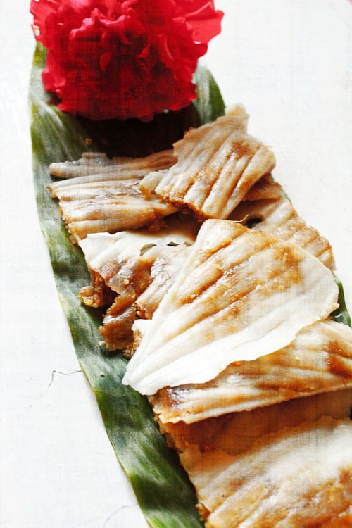 patoleo served on a fresh turmeric leaf with a hibiscus flower kept on the top end. 
