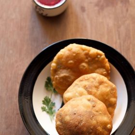 matar kachori garnished with coriander leaves and served on a plate with chutney in a small bowl.