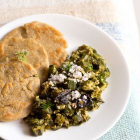 bhindi bhaji garnished with fresh grated coconut and served with jowar bhakris on a white plate.