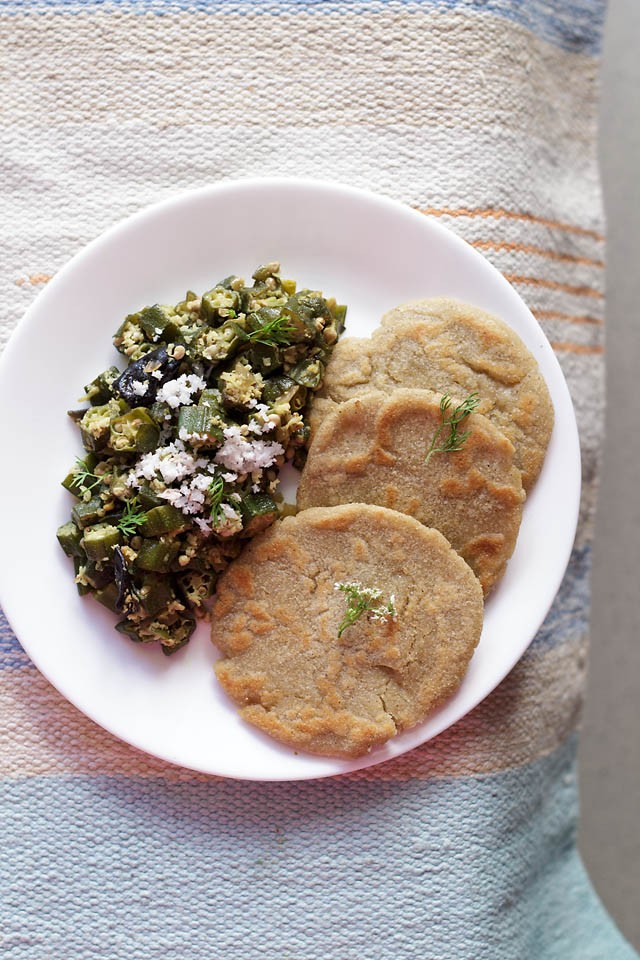 bhindi bhaji garnished with fresh grated coconut and served with jowar bhakris on a white plate. 