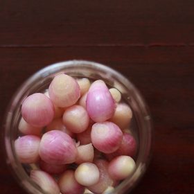 overhead shot of red pickled onions in a glass jar