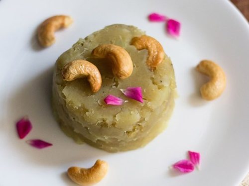 sweet potato halwa garnished with fried cashews, rose petals and served on a white colored plate.