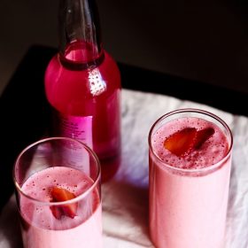 strawberry lassi garnished with strawberry slices and served in glasses.