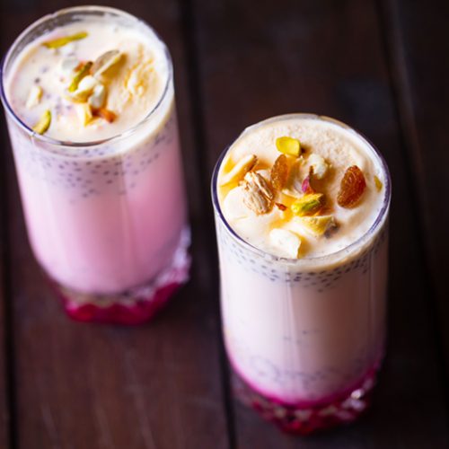 Pink layered faluda drink with chopped nuts on top