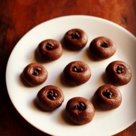 chocolate sandesh garnished with chocolate chips and served on a white plate.