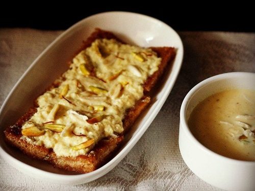 shahi tukda in a white oblong serving plate with a bowl of homemade rabri