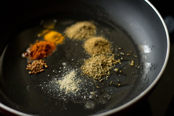 spice powders added in hot oil in pan.