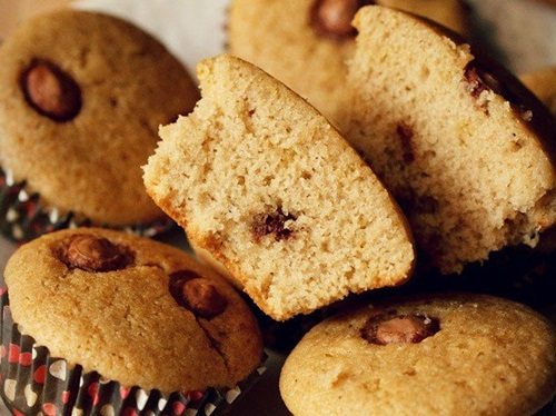 eggless chocolate chip muffin cut in half, laying on top of other chocolate chip muffins.