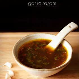garlic rasam served in a white ceramic bowl with a spoon in it and text layover.