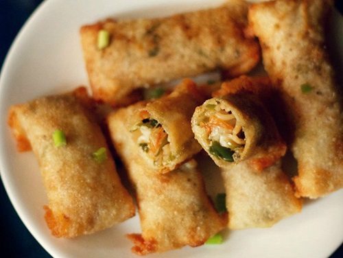 spring rolls on a white plate with halved roll showing the vegetable filling inside