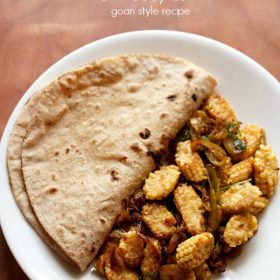 baby corn sabji served on a white plate with folded chapati by the side with text layovers