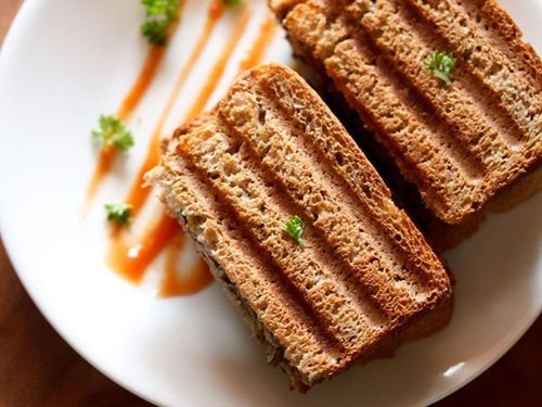 mushroom sandwich sliced and served on a plate with tomato ketchup.