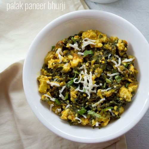 palak paneer bhurji garnished with grated paneer and served in a white bowl along with a side of a bowl of onions.