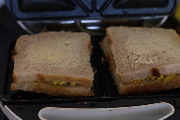 assembled paneer bhurji sandwiches placed on a griller. 