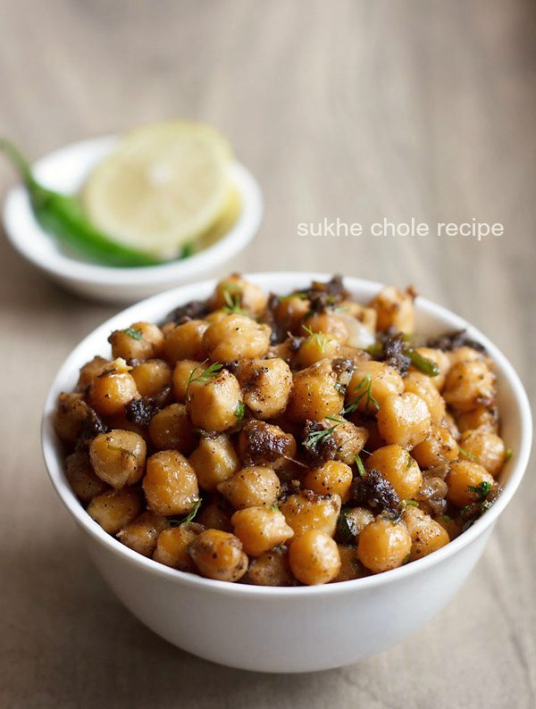 sukha chana served in a white bowl with a side bowl of onion slice and green chili.