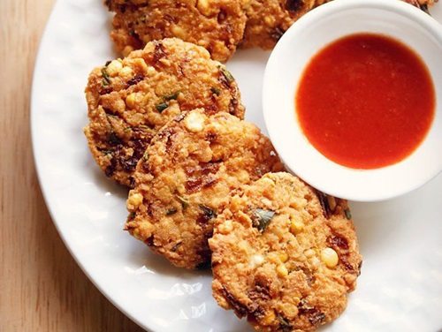 dal vada arranged neatly on a white plate next to a small white bowl of red chutney