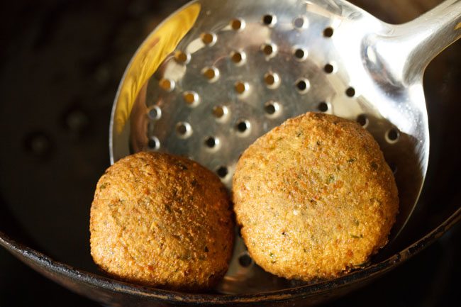 removing fried green falafel with slotted spoon. 
