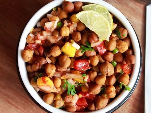 kala chana chaat with lemon wedges in a bowl.