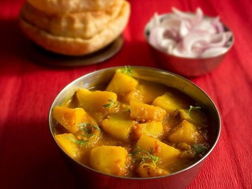 aloo poori served with sliced onions.