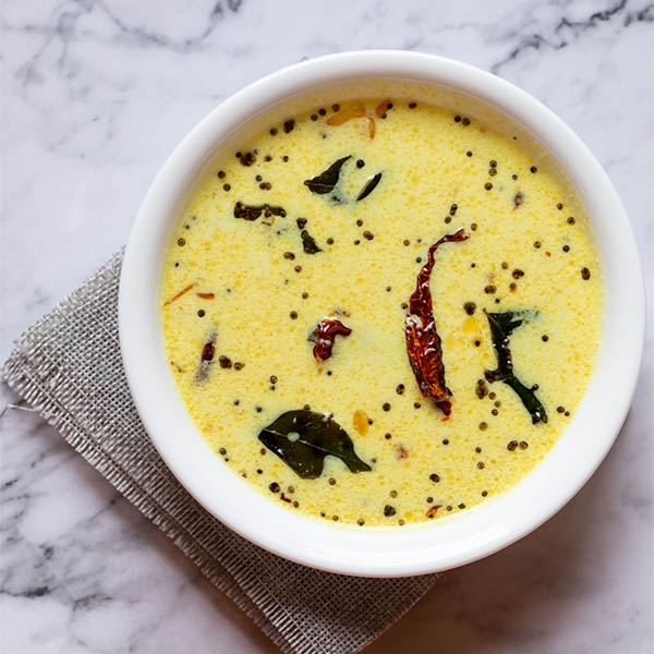 moru curry or pulissery in a white bowl on a white marble table