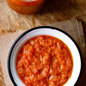 overhead shot of homemade marinara in a white bowl with a black rim on a piece of burlap.