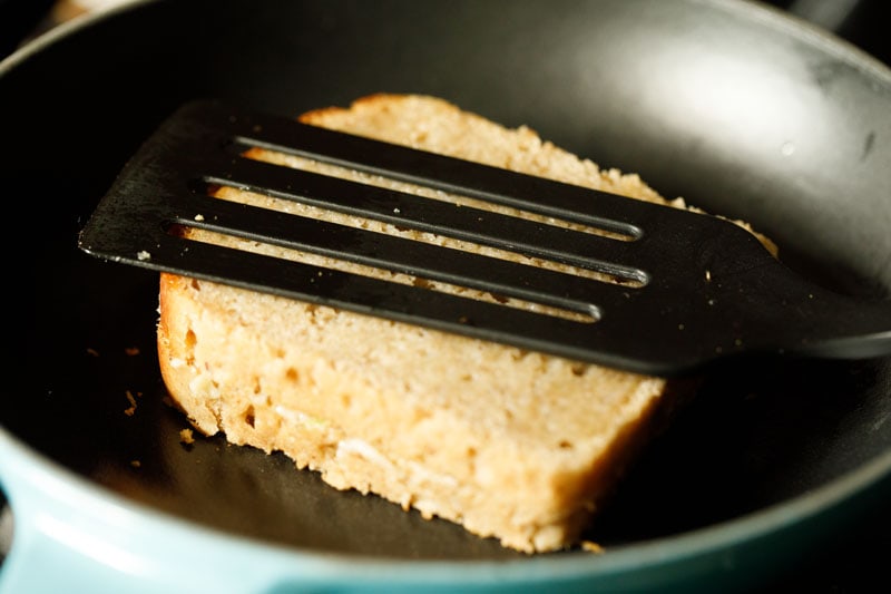 cheese sandwich being pressed with a spatula in the pan