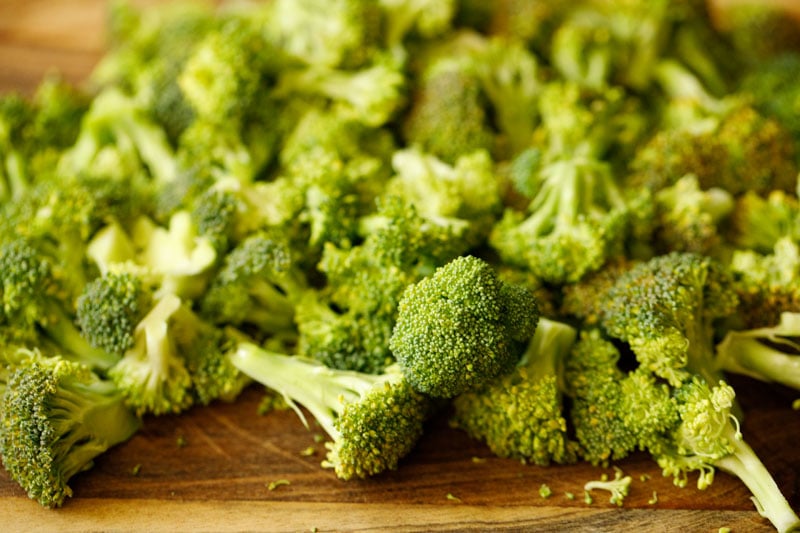 chopped broccoli florets on wooden board