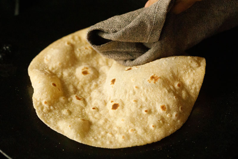 chapati being pressed with a cotton napkin and helping the chapati to puff