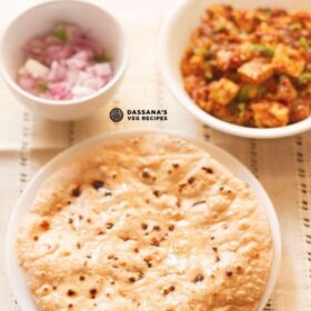top shot of roti smeared with ghee on a white plate with two white bowls of paneer curry and chopped red onions placed above on a cream cotton fabric with text layovers