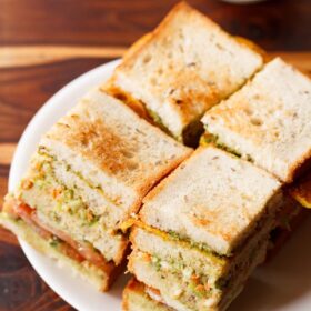 club sandwich squares with layers seen on a white plate with tomato ketchup.