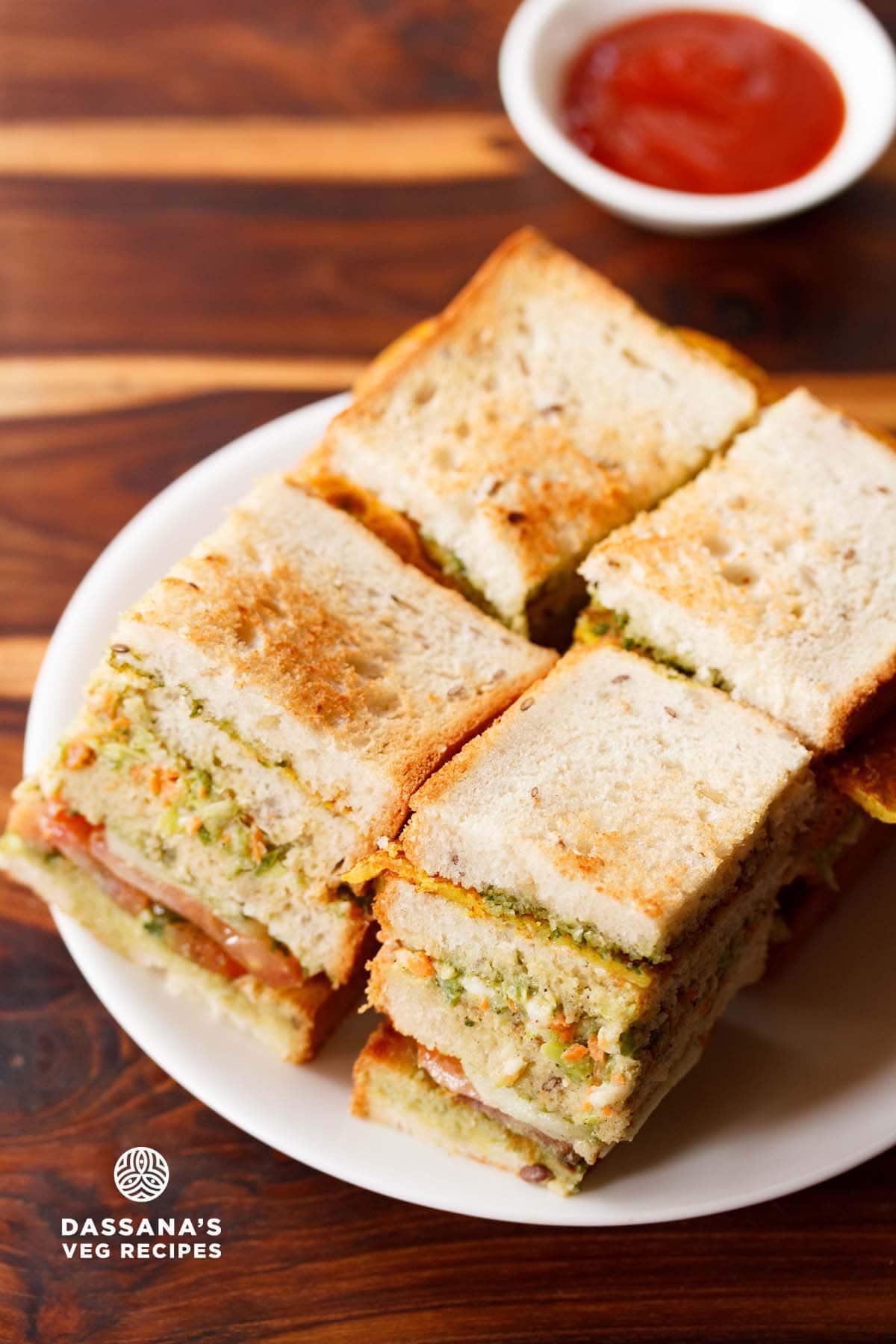 club sandwich squares with layers seen on a white plate with tomato ketchup.