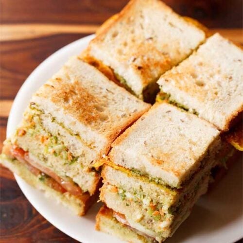 club sandwich squares with layers seen on a white plate.