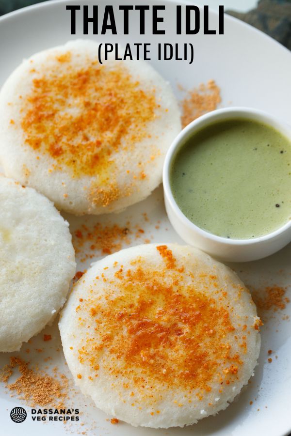 three thatte idli sprinkled with podi and ghee served on a plate with cilantro coconut chutney in a white bowl.