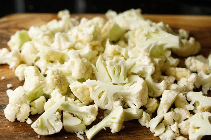 chopped cauliflower florets on chopping board.