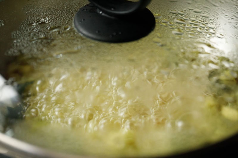 glass lid on pan with cauliflower florets cooking inside.