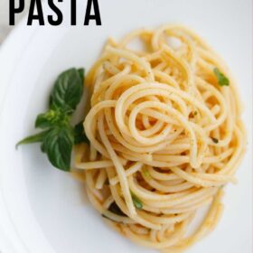 garlic butter pasta served on a white plate with a basil sprig by the side with text layovers.