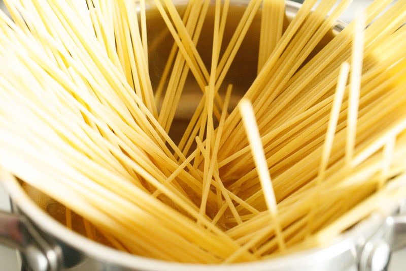 spaghetti strands inside hot water in pan.