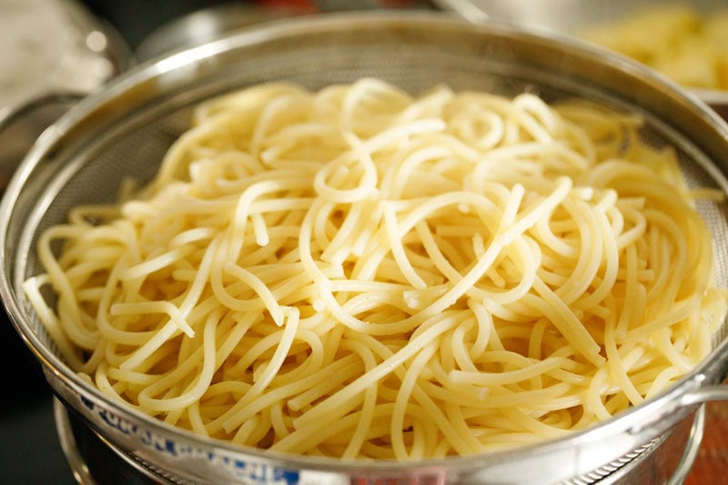 cooked spaghetti strained in a strainer.