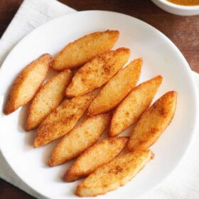 idli fry served on a white plate with a bowl of tomato chutney kept on the top left side with text layovers.