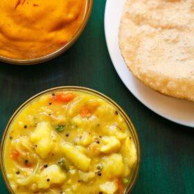 poori masala or poori curry combination on a green tray with a bow of aamras (thick mango pulp).