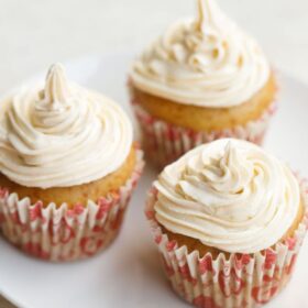 three vanilla cupcakes frosted with buttercream icing with text layovers.