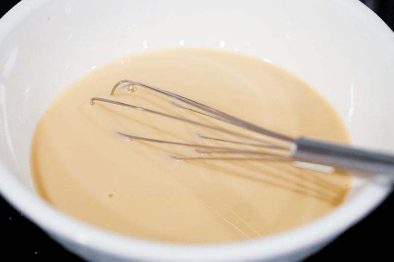 mixing sugar in milk with wired whisk.