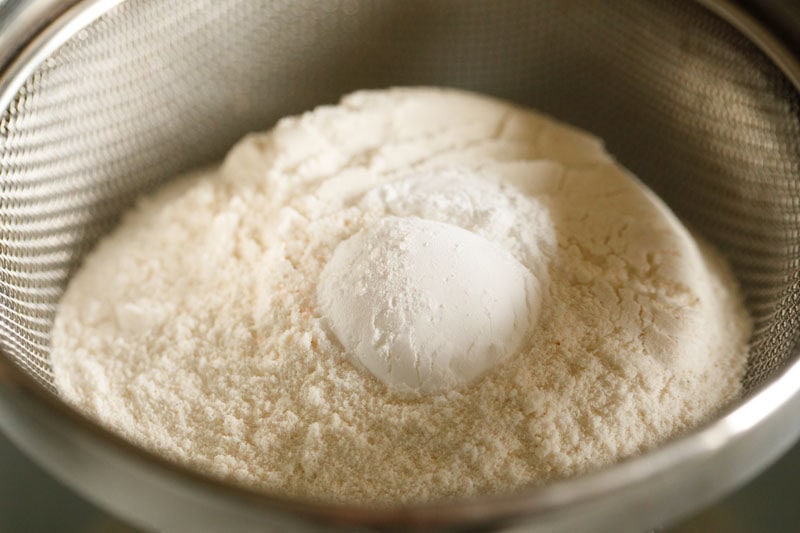 all-purpose flour and other dry ingredients being sifted in a bowl to make vanilla cupcakes. 