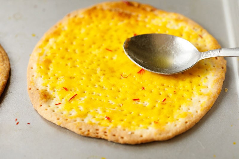 saffron liquid being spread on sheermal bread.