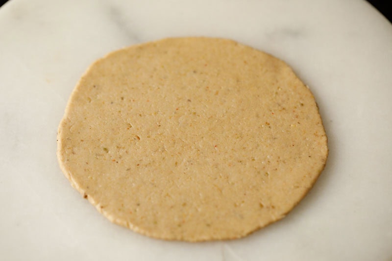 dough rolled into disc or bedmi poori on a marble rolling board.