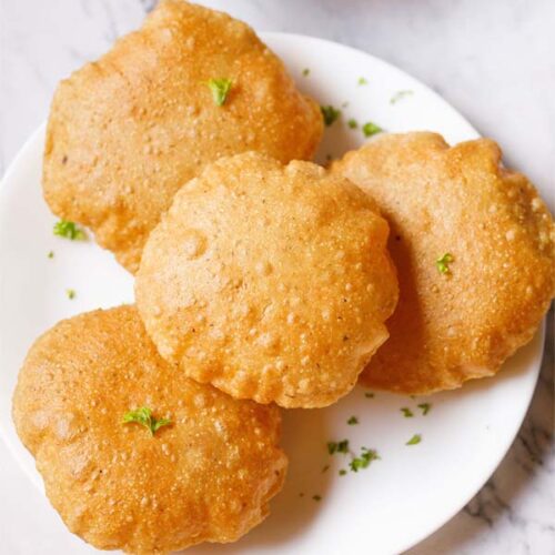 bedmi puri with a sprinkling of coriander leaves on a white plate.